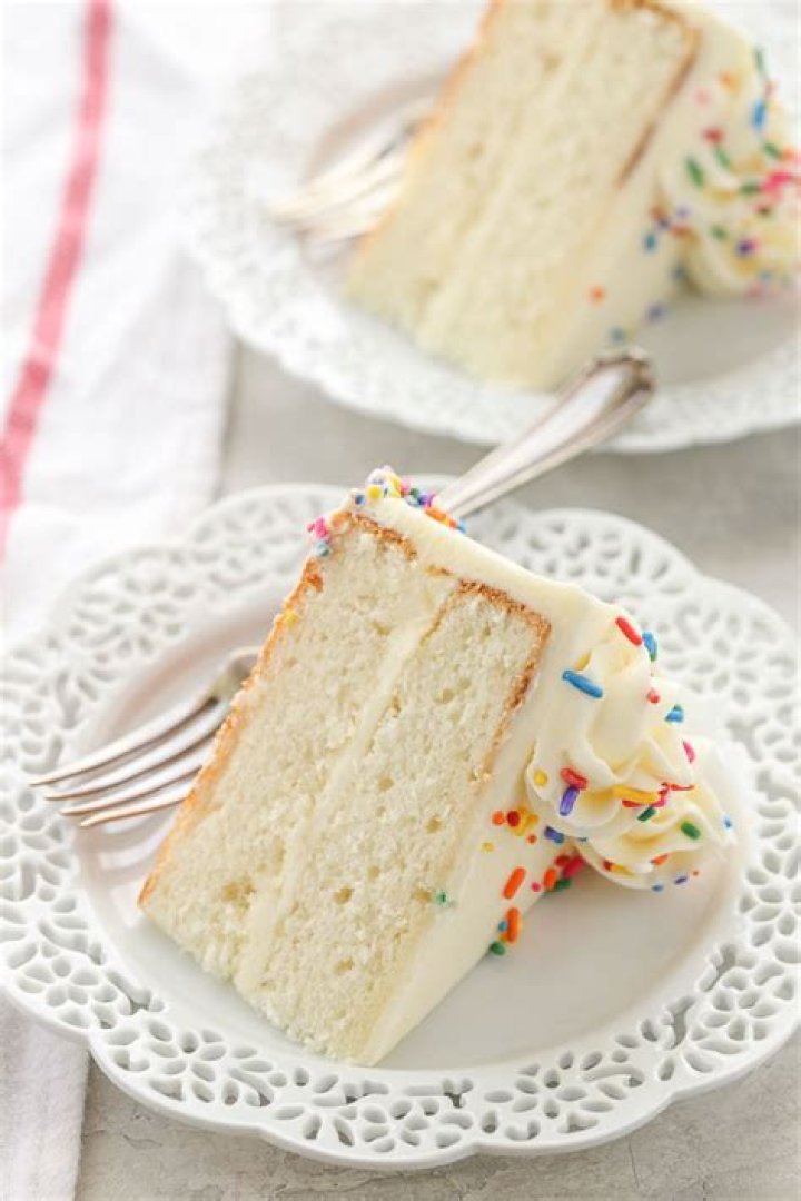 White layer cake topped with raspberries and covered in shredded coconut.